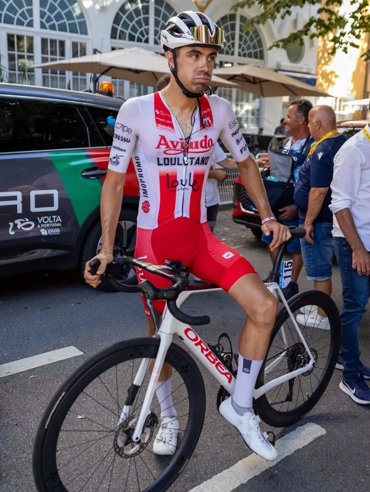 Daniel Viegas standing with his Orbea bike, official Volta a Portugal team car behind him